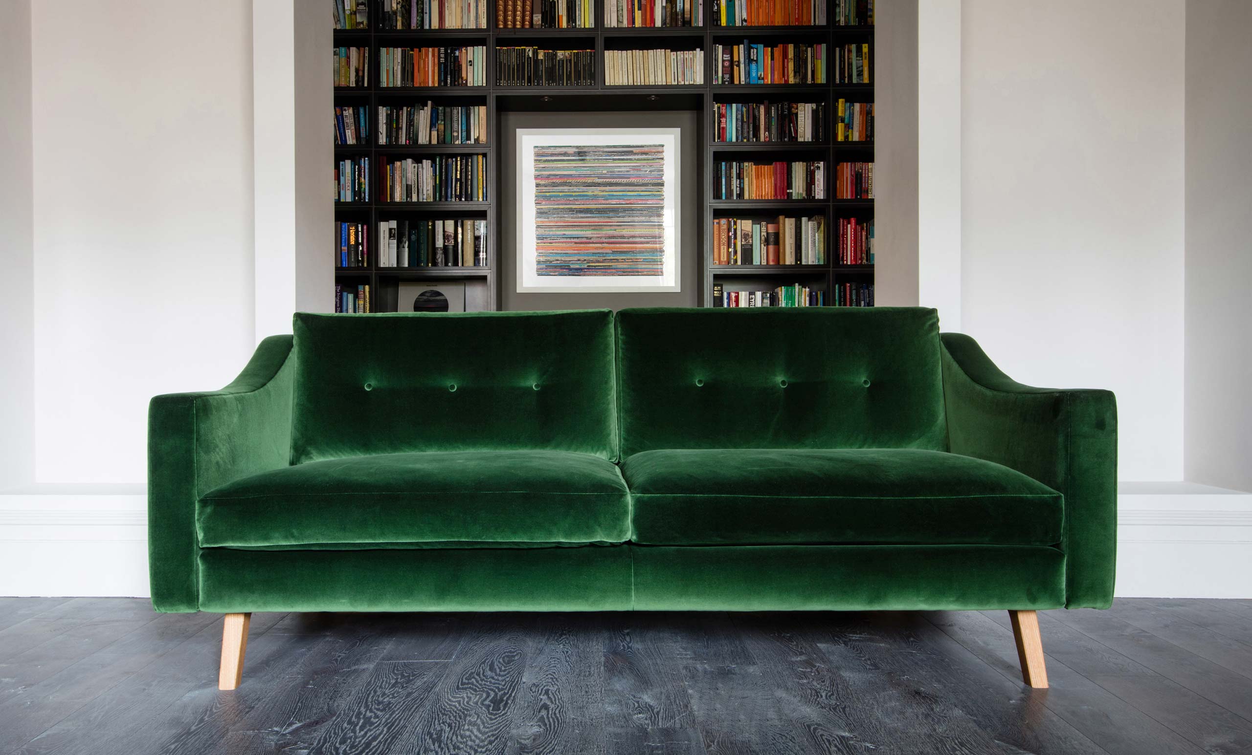 Emerald green buttoned velvet bespoke sofa and library shelving by Six Hands